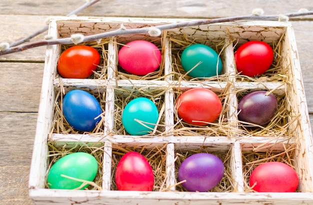Ramitas de sauce y huevos de Pascua en una caja de madera sobre una mesa de madera antigua