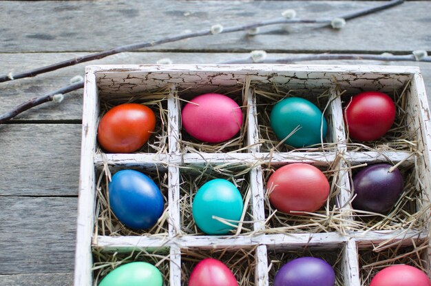 Ramitas de sauce y huevos de Pascua en una caja de madera sobre una mesa de madera antigua