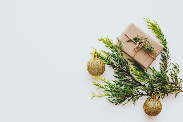 Ramitas verdes brillantes de pino y una caja de regalo marrón claro y bolas doradas