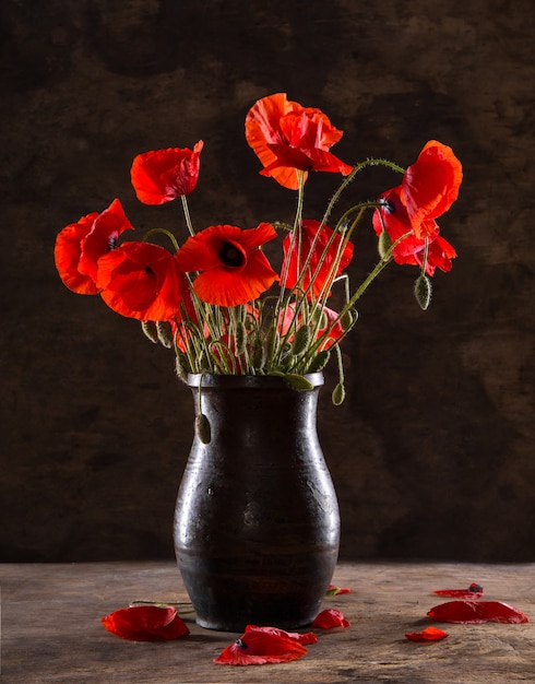 Ramo de amapolas en florero sobre un fondo de madera.