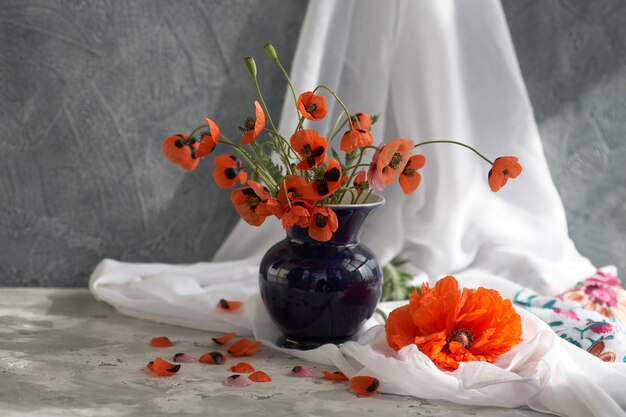 Ramo de amapolas rojas en florero de cerámica azul