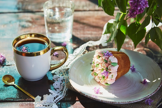 Ramo ao ar livre de verão com uma xícara de café lindo copo de cupcake de água e flores brilhantes Piquenique do núcleo da casa de campo com tons brilhantes de verão de flores em um dia ensolarado Sombras duras