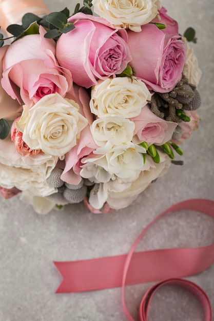 Ramo de boda delicado de rosas blancas y rosadas sobre una mesa de piedra.