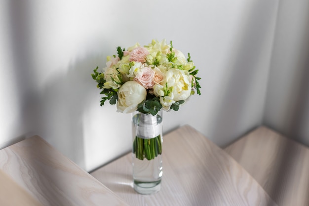 Ramo de la boda en un florero de cristal en las escaleras cerca de la pared.