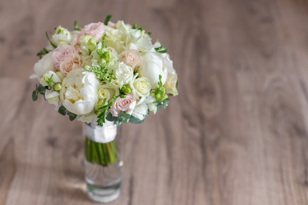 Ramo de la boda en un florero de cristal en las escaleras cerca de la pared.