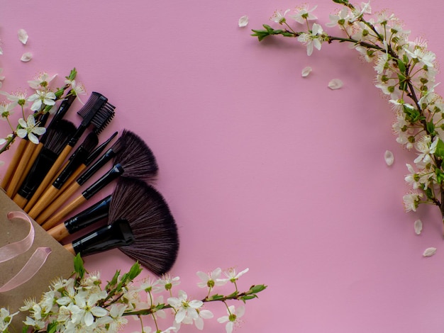 Ramo de cepillos cosméticos en bolsa de papel sobre fondo rosa