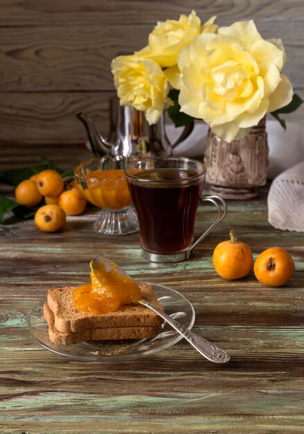 Ramo com frutas medlars geleia e chá em uma mesa de madeira