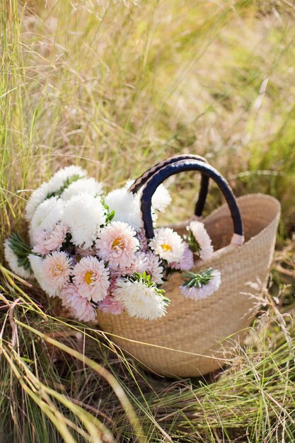 Ramo de crisantemos blancos y rosas en bolsa de paja Bolsa con flores sobre un concepto de otoño de hierba seca