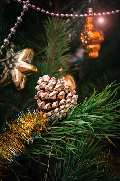 Ramo de abeto com cone, brinquedos e bolas. Luzes festivas com brilhos no fundo. Conceito de cartão de Natal.