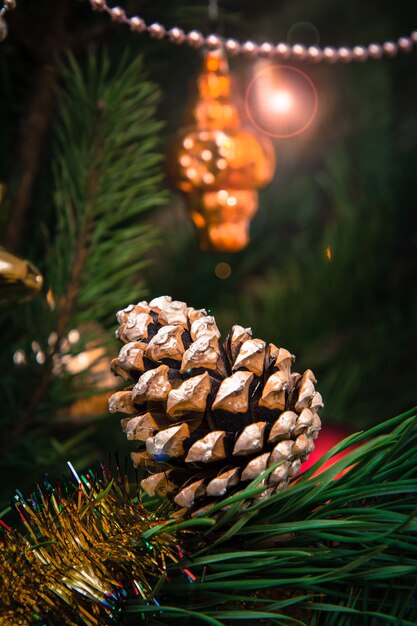 Foto ramo de abeto com cone, brinquedos e bolas. luzes festivas com brilhos no fundo. conceito de cartão de natal.