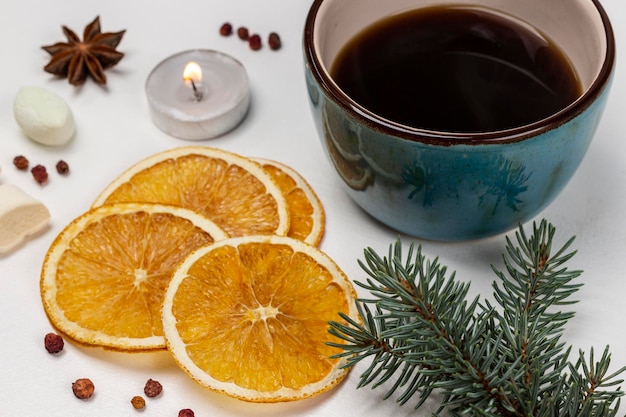 Ramo de abeto e fatias de laranja secas caneca de café com vela acesa