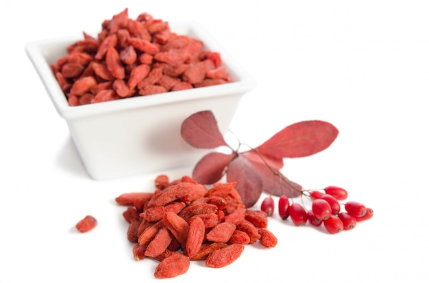 Ramo de bérberis vermelhas maduras e bagas de goji secas, isoladas no espaço em branco