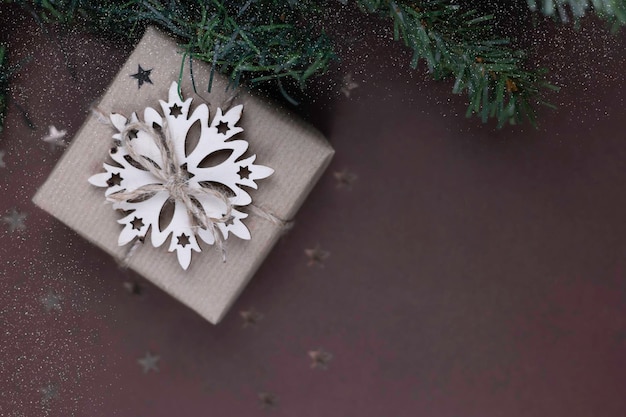 Ramo de Natal e caixa de presente fechada com decoração de floco de neve de madeira sobre um fundo azul.