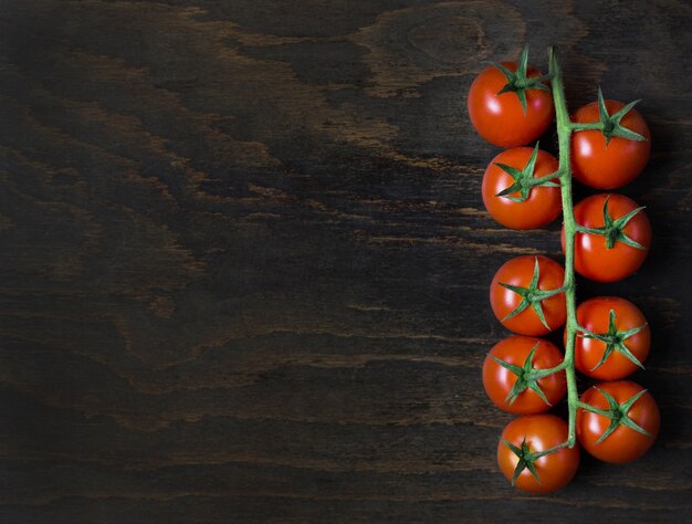 Ramo de tomate cereja fresco maduro vermelho em uma placa de madeira