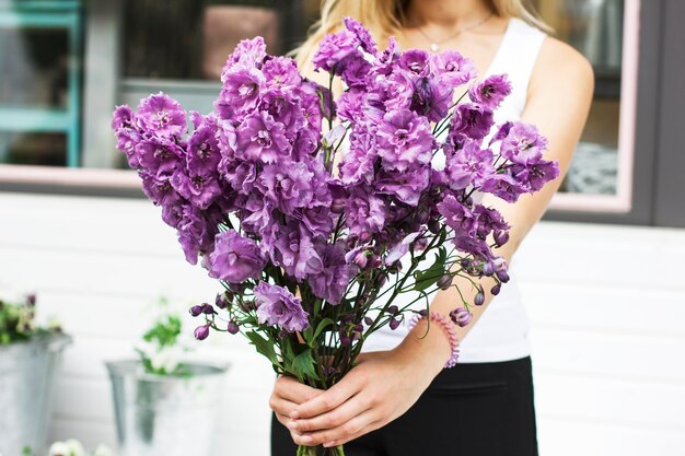 Ramo de delphinium lila púrpura en manos de mujeres en la calle