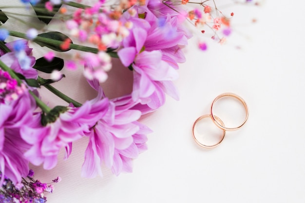 Foto ramo de flores al lado de los anillos de compromiso