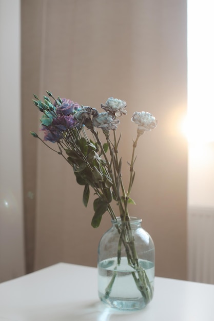 ramo de flores azules y moradas en un frasco sobre la mesa en una habitación soleada decoración minimalista para el hogar
