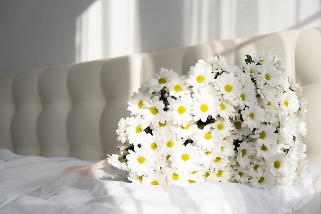 Ramo de flores blancas en dormitorio de mujeres con sombras.