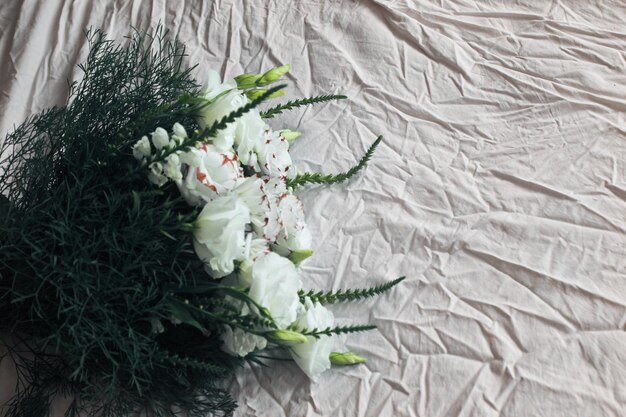 Ramo de flores blancas sobre un fondo blanco contra el fondo de la cama