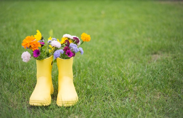 Un ramo de flores en botas amarillas sobre fondo de hierba verde