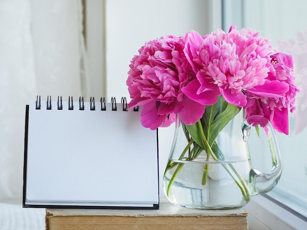 Foto un ramo de flores brillantes y una página en blanco en el cuaderno