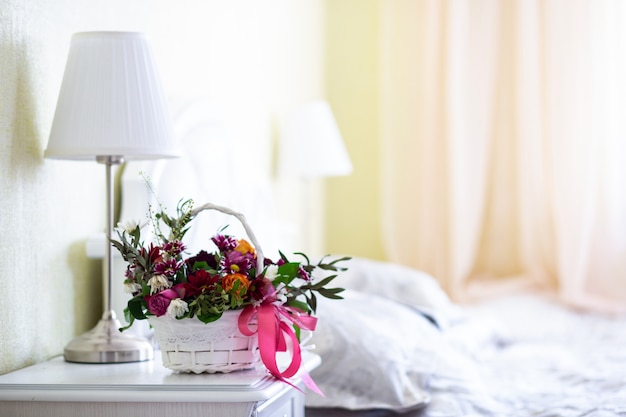 Foto ramo de flores en una canasta blanca con luz interior del dormitorio