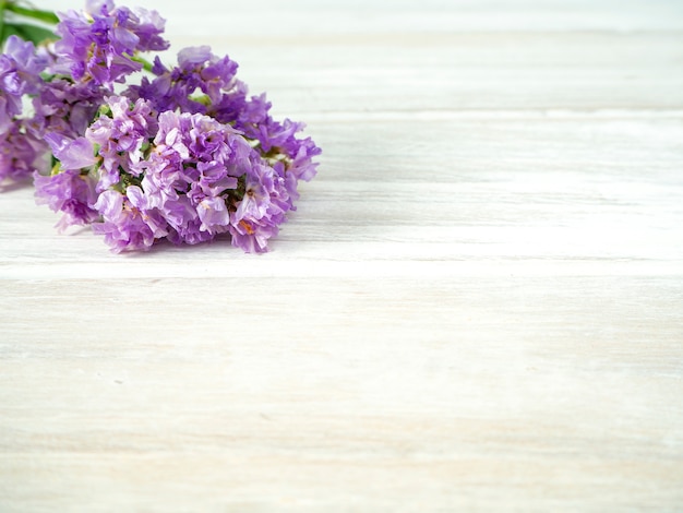 Ramo de flores de color púrpura en una mesa de madera blanca
