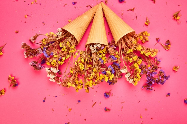 Ramo de flores en un cono de waffle sobre una superficie rosa