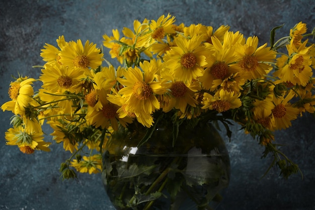 Ramo de flores Doronicum (familia de los girasoles) en un florero de vidrio transparente.