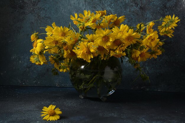 Ramo de flores Doronicum (familia de los girasoles) en un florero de vidrio transparente.