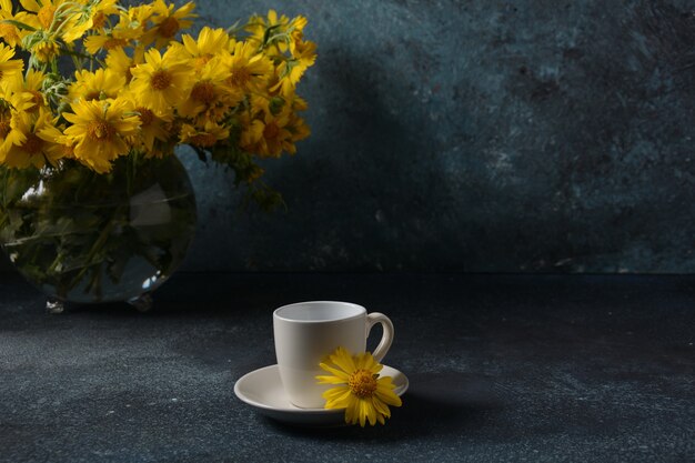Ramo de flores Doronicum y taza de café. Concepto de verano