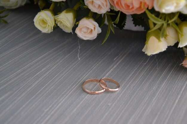 Foto un ramo de flores y dos anillos de bodas de oro sobre una mesa.