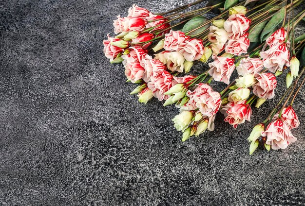 Foto un ramo de flores de eustoma rojas y blancas sobre un fondo de hormigón oscuro lugar para el texto vista superior