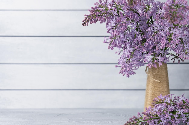 Ramo de flores lilas en jarrón sobre fondo de madera gris Copiar espacio para telón de fondo