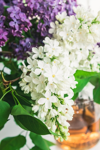 Un ramo de flores lilas y lilas blancas en un florero de vidrio cerca de la ubicación