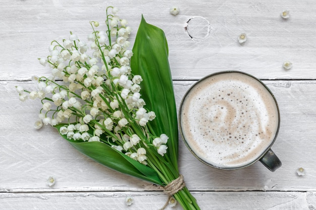 Ramo de flores de lirio de los valles de primavera con taza de café con leche