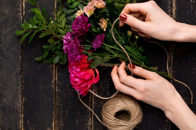 Ramo de flores en mano femenina en una mesa de madera negra