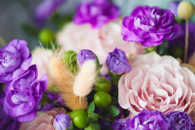 Un ramo de flores moradas con hojas verdes y una espiga de trigo.