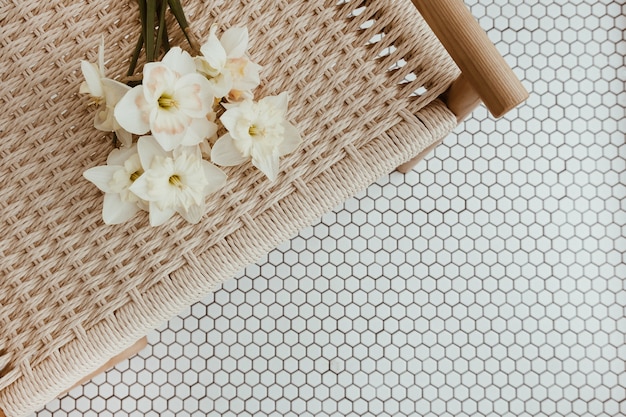 Ramo de flores de narciso en banco de ratán en mosaico