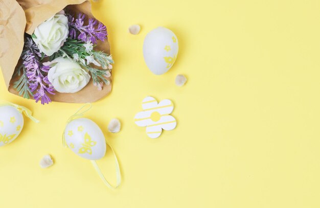 Ramo de flores de primavera artificiales en papel artesanal con capullos de sauce y huevos de Pascua decorativos en un amarillo