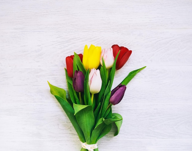 Ramo de flores de primavera Hermosos tulipanes sobre fondo blanco de madera con espacio de copia Vista superior plana