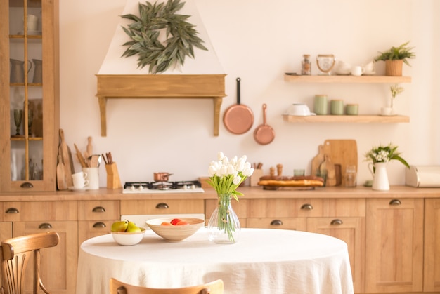 Ramo de flores de primavera en un jarrón y frutas en la mesa de la cocina