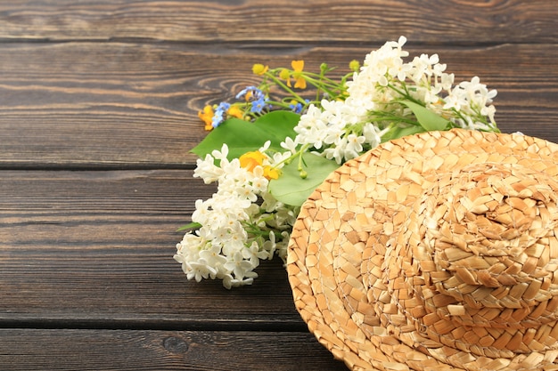 Ramo de flores de primavera en un sombrero de paja sobre un fondo de madera