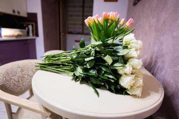 Ramo de flores de rosas blancas sobre mesa de madera contra tulipanes