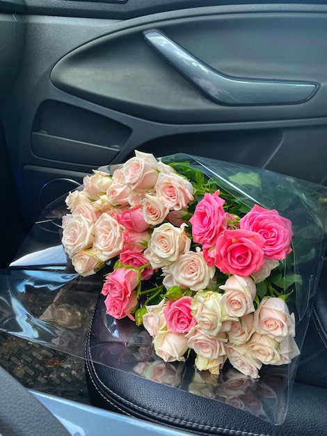 Un ramo de flores rosas para dama en el asiento delantero del auto.