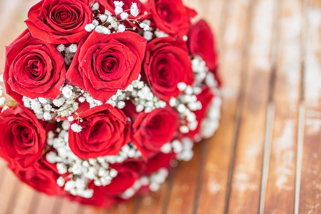 Ramo de flores rosas rojas sobre fondo de madera. Vista superior de la tarjeta de felicitación de boda o día de San Valentín