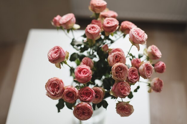 Ramo de flores rosas rosas en florero de vidrio en una acogedora sala de estar