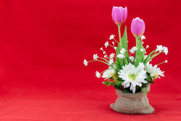 Ramo de flores en un saco sobre fondo rojo para el amor o el concepto de San Valentín