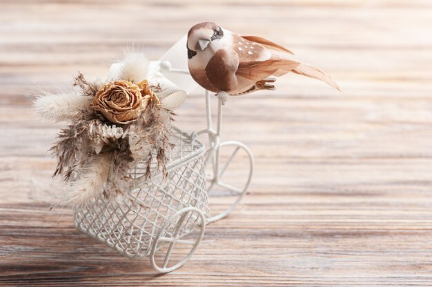 Ramo de flores secas en bicicleta decorativa con pequeño pájaro marrón con espacio de copia. Tarjeta de felicitación para boda o vacaciones en tonos naturales.