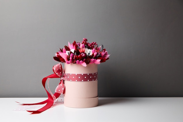 Ramo de flores secas con pastos en caja de sombrero redonda rosa